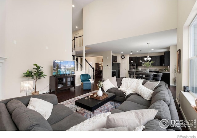 living room featuring a towering ceiling, stairway, and dark wood-type flooring