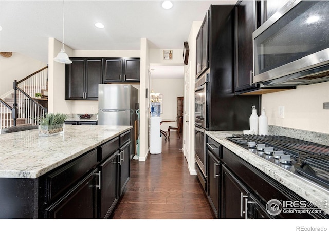 kitchen with dark wood finished floors, light stone counters, decorative light fixtures, stainless steel appliances, and recessed lighting