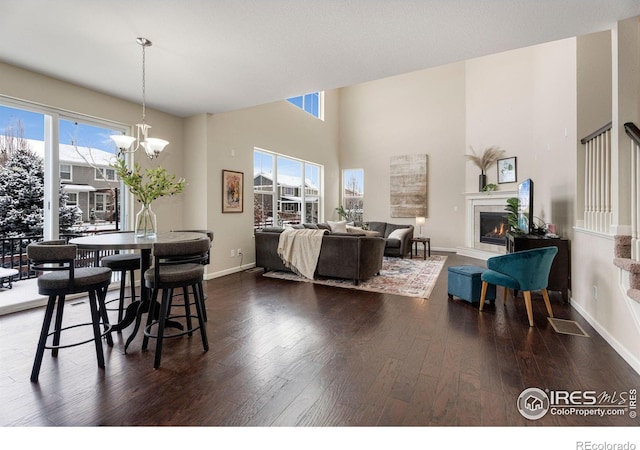 dining room with a healthy amount of sunlight, dark wood-style floors, and a lit fireplace