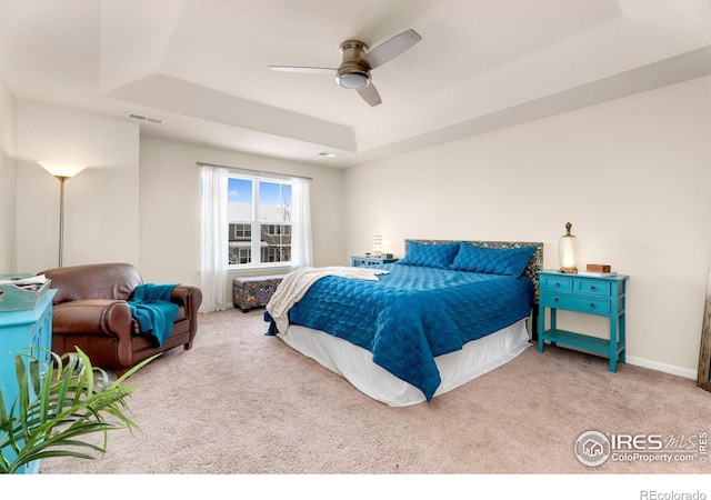 bedroom with visible vents, baseboards, a ceiling fan, a tray ceiling, and carpet