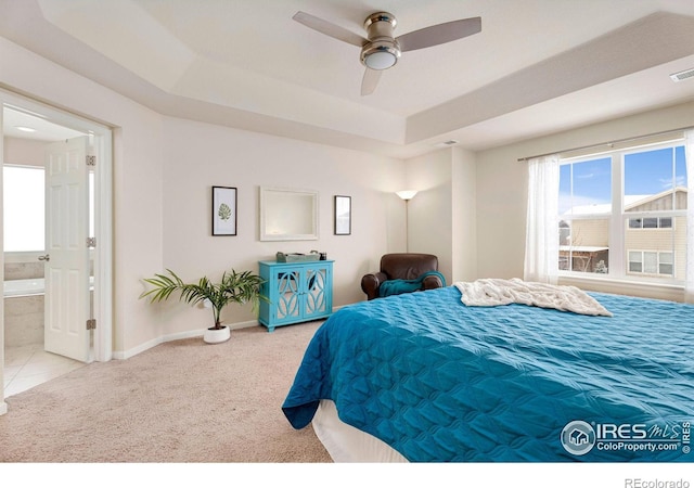 bedroom featuring multiple windows, a tray ceiling, and light colored carpet