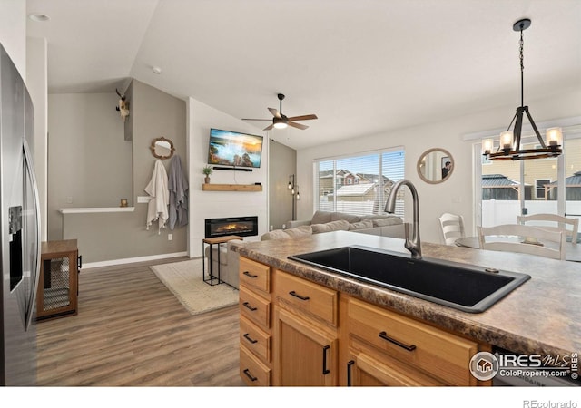 kitchen with lofted ceiling, sink, stainless steel fridge, pendant lighting, and a fireplace