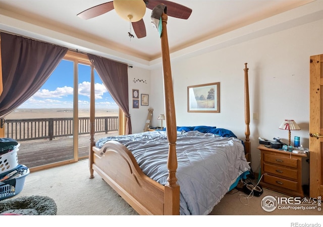 carpeted bedroom with access to exterior, a water view, ceiling fan, and a tray ceiling