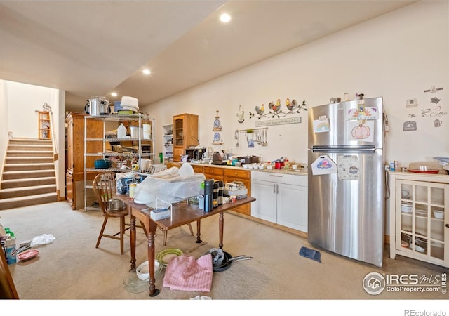 kitchen with light colored carpet, white cabinetry, and stainless steel refrigerator