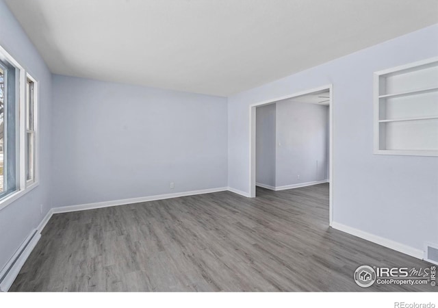 empty room featuring a baseboard radiator, built in features, and dark hardwood / wood-style floors