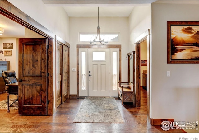 foyer entrance with dark hardwood / wood-style flooring and a chandelier