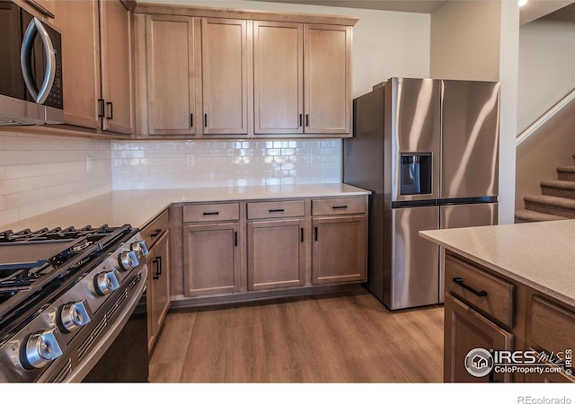 6955 Stonebrook Dr, Timnath, CO 80547 - kitchen featuring stainless steel appliances, wood finished floors, light countertops, and decorative backsplash