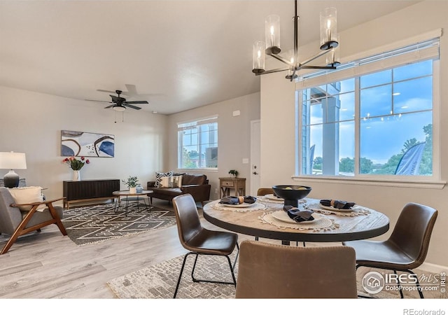 dining area featuring ceiling fan with notable chandelier and light wood-type flooring