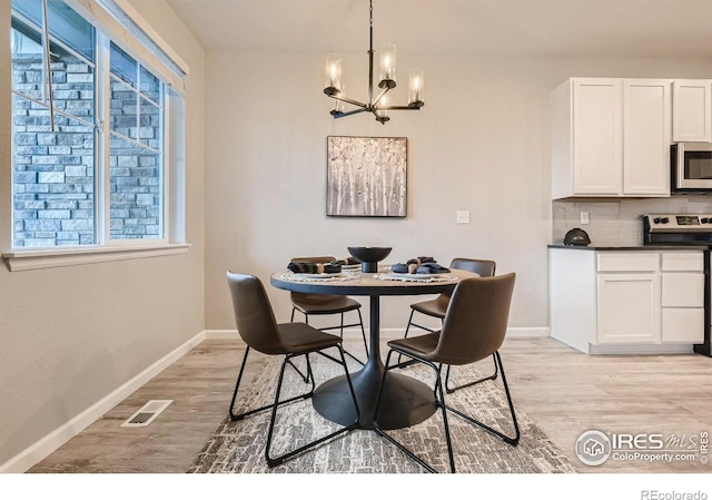 dining room with light wood-type flooring and an inviting chandelier