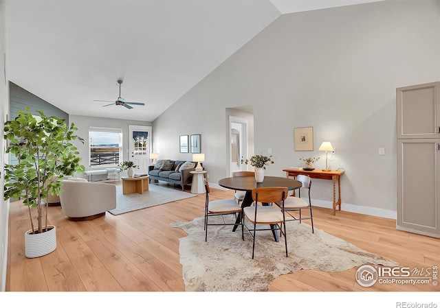 dining room featuring ceiling fan, light wood-type flooring, and high vaulted ceiling