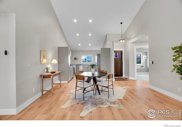 dining area featuring light hardwood / wood-style flooring and high vaulted ceiling