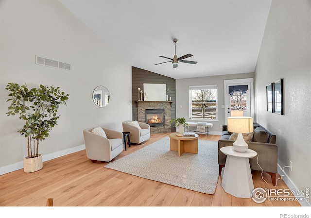 living room with a stone fireplace, ceiling fan, hardwood / wood-style floors, and lofted ceiling