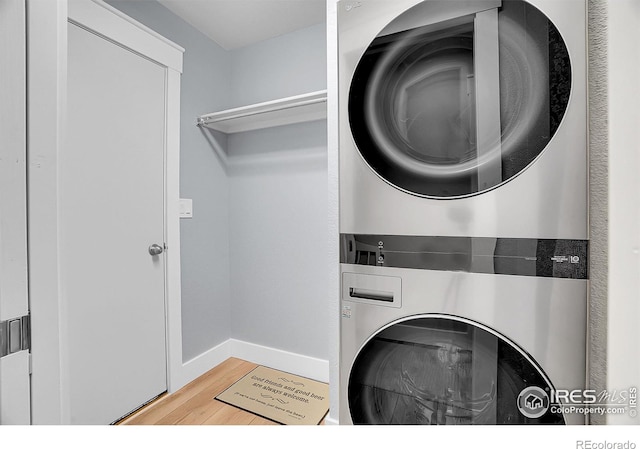 laundry room with stacked washing maching and dryer and hardwood / wood-style flooring