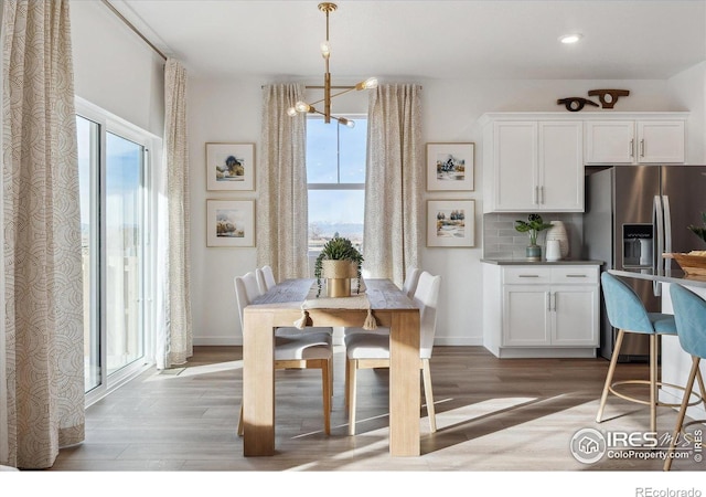 dining space featuring a healthy amount of sunlight, wood-type flooring, and a chandelier