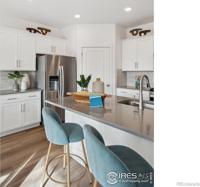 kitchen featuring tasteful backsplash, sink, white cabinets, and a kitchen bar