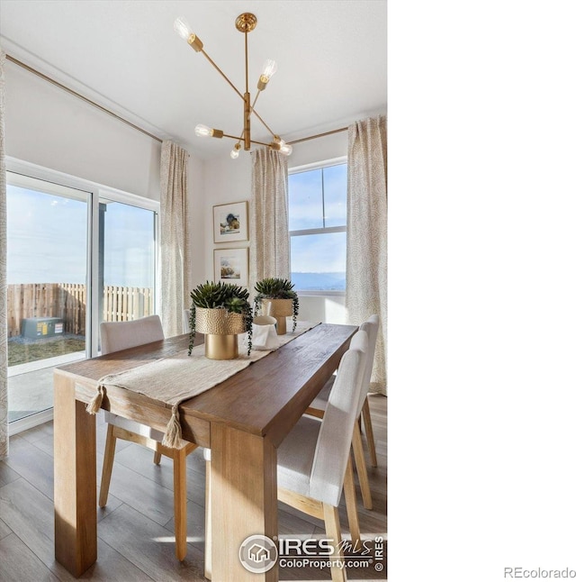 dining room featuring wood-type flooring, a water view, and a notable chandelier