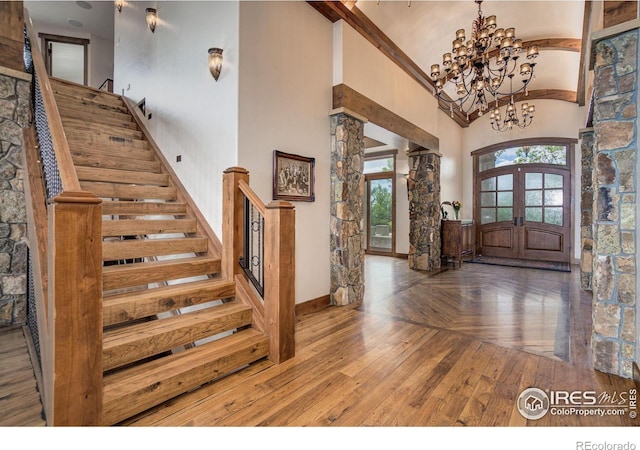 entryway with french doors, high vaulted ceiling, wood-type flooring, and an inviting chandelier