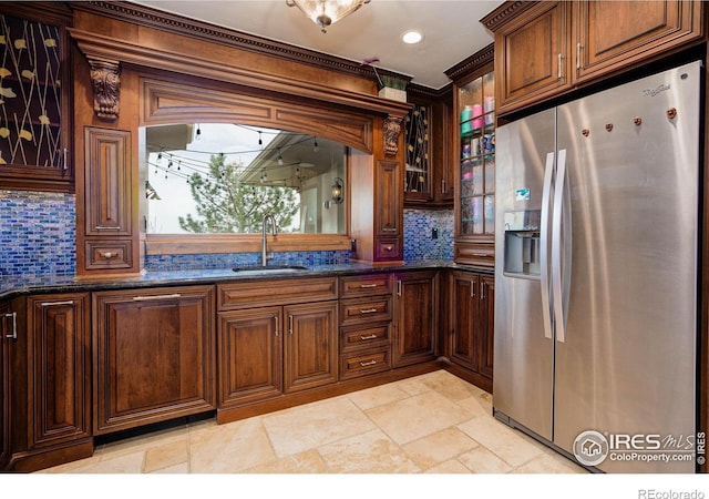 kitchen with decorative backsplash, stainless steel fridge, dark stone counters, and sink