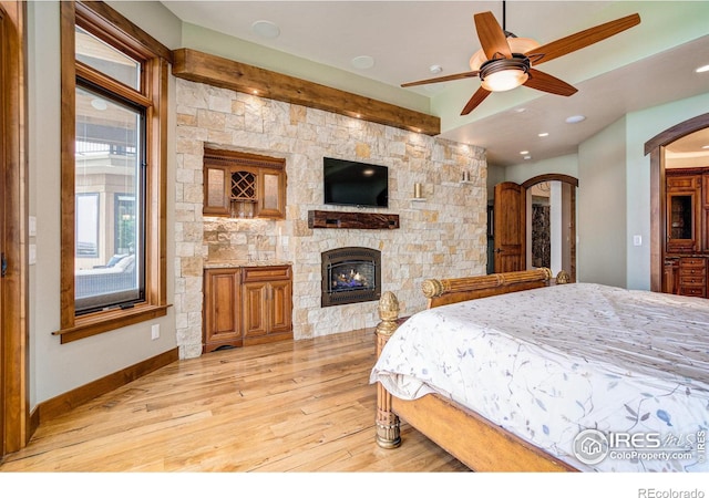 bedroom featuring a fireplace, light hardwood / wood-style flooring, and ceiling fan