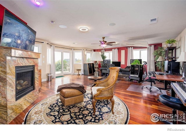 living room featuring ceiling fan, plenty of natural light, a high end fireplace, and wood-type flooring