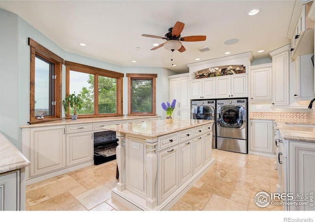 kitchen with sink, ceiling fan, a kitchen island, white cabinetry, and washing machine and clothes dryer