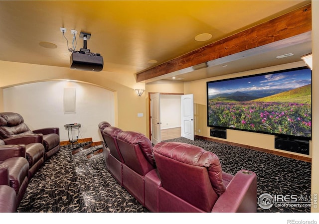 carpeted home theater with beamed ceiling