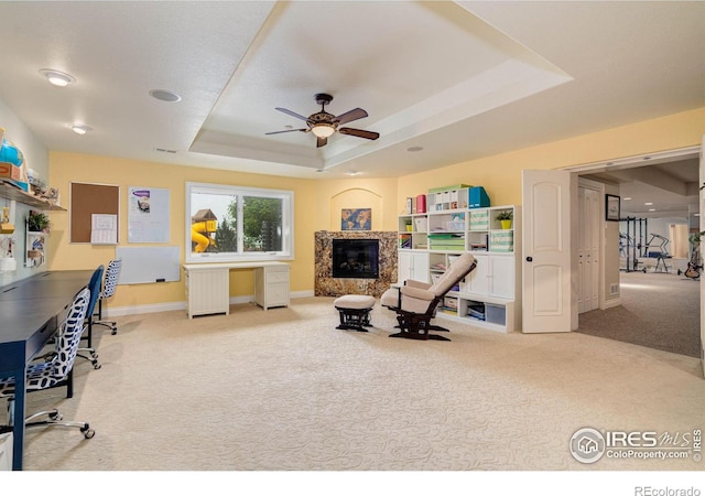 carpeted living room featuring ceiling fan, radiator heating unit, a high end fireplace, and a tray ceiling