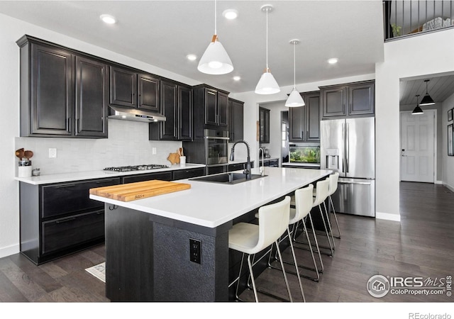 kitchen featuring sink, stainless steel appliances, dark hardwood / wood-style floors, an island with sink, and decorative light fixtures