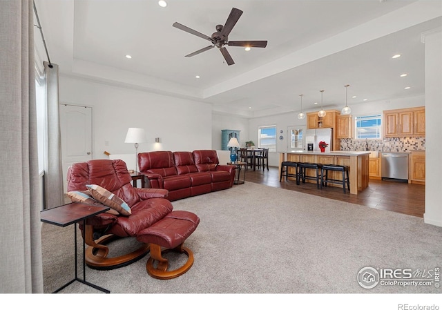 living room featuring dark carpet, a raised ceiling, a ceiling fan, and recessed lighting