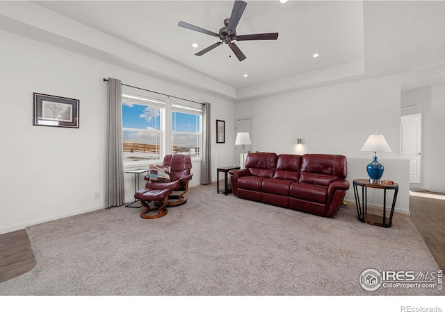 living room featuring baseboards, a tray ceiling, and recessed lighting