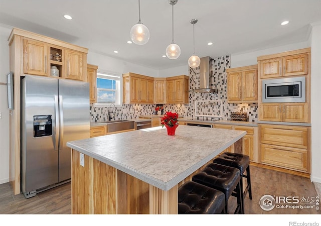 kitchen with a sink, light countertops, appliances with stainless steel finishes, wall chimney range hood, and tasteful backsplash