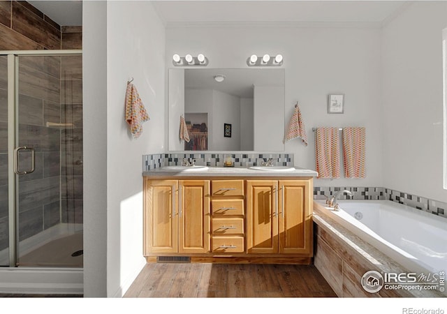 bathroom featuring crown molding, tasteful backsplash, a stall shower, a sink, and wood finished floors