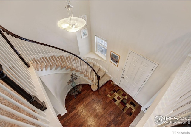 entryway with wood-type flooring and a towering ceiling