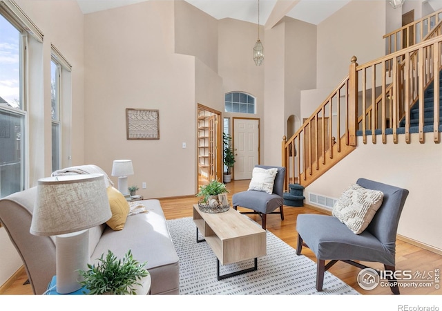 living room featuring light wood-type flooring and a high ceiling