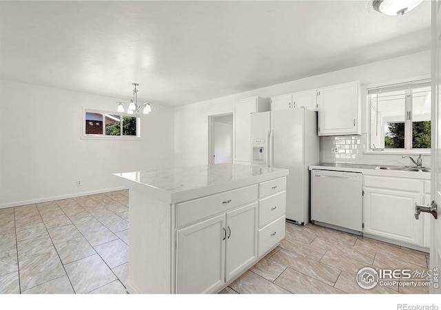 kitchen featuring a kitchen island, pendant lighting, white appliances, decorative backsplash, and white cabinets