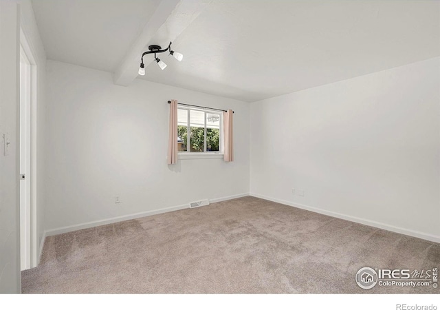 carpeted spare room featuring beamed ceiling