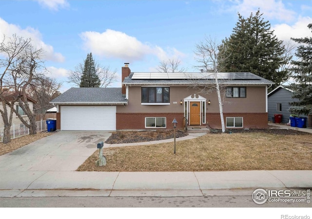 bi-level home with solar panels, a front lawn, and a garage