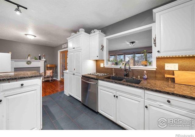 kitchen with backsplash, dark stone counters, white cabinets, sink, and stainless steel dishwasher