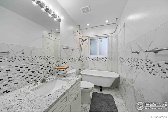 bathroom with a washtub, toilet, tile walls, and vanity