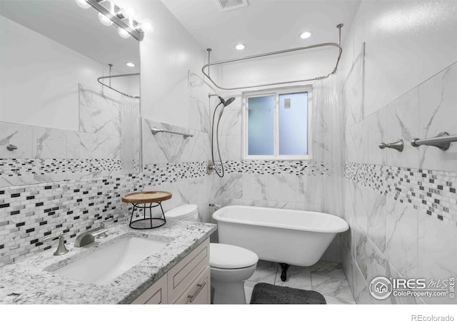 bathroom featuring vanity, toilet, and tile walls