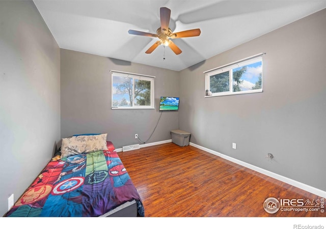 unfurnished bedroom with hardwood / wood-style floors, ceiling fan, and multiple windows