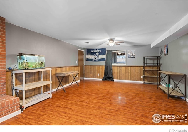 interior space with ceiling fan, wooden walls, and hardwood / wood-style flooring