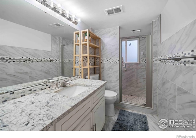 bathroom with vanity, toilet, a shower with door, and tile walls