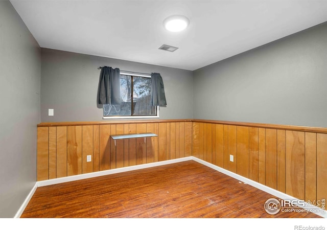 spare room featuring hardwood / wood-style floors and wood walls