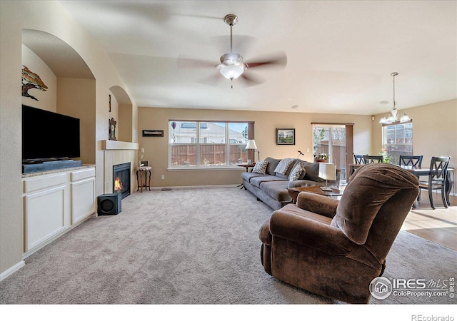 carpeted living room with ceiling fan with notable chandelier and lofted ceiling