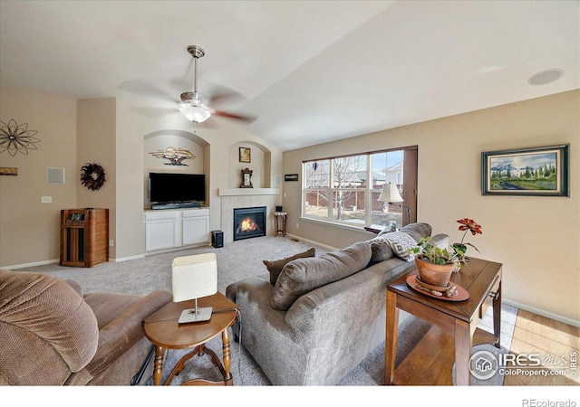 living room featuring ceiling fan, a fireplace, and light carpet