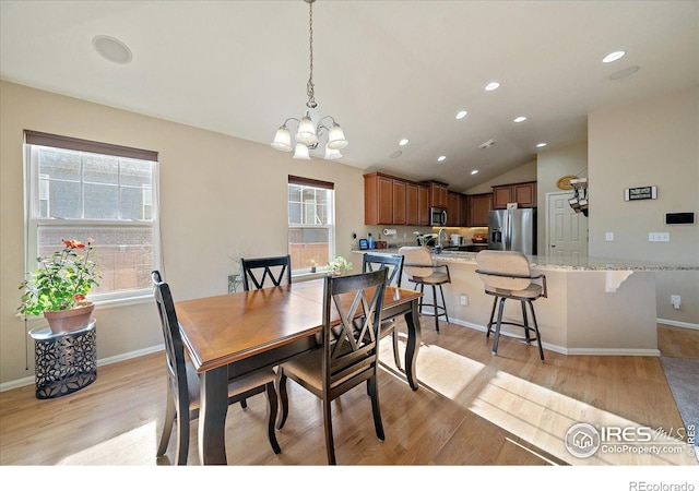 dining room featuring light hardwood / wood-style floors, vaulted ceiling, a notable chandelier, and sink