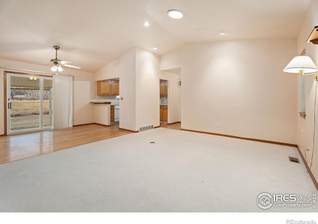 unfurnished living room with ceiling fan, light colored carpet, and vaulted ceiling