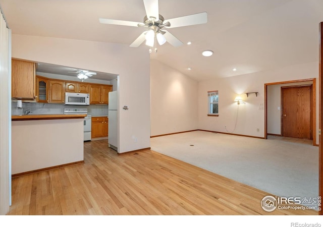 kitchen with backsplash, white appliances, sink, light hardwood / wood-style flooring, and lofted ceiling