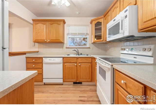 kitchen featuring white appliances, sink, ceiling fan, tasteful backsplash, and light hardwood / wood-style floors